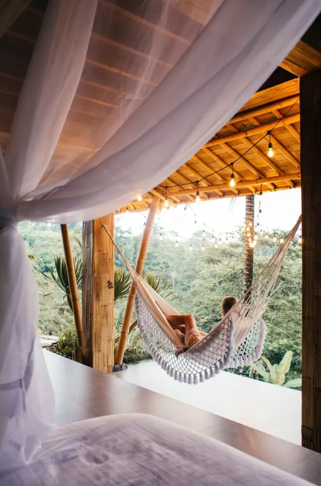 Unrecognizable traveler in hammock against bed in tropical resort